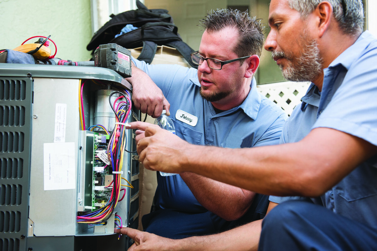 Two HVAC technicians installing indoor heating and cooling equipment