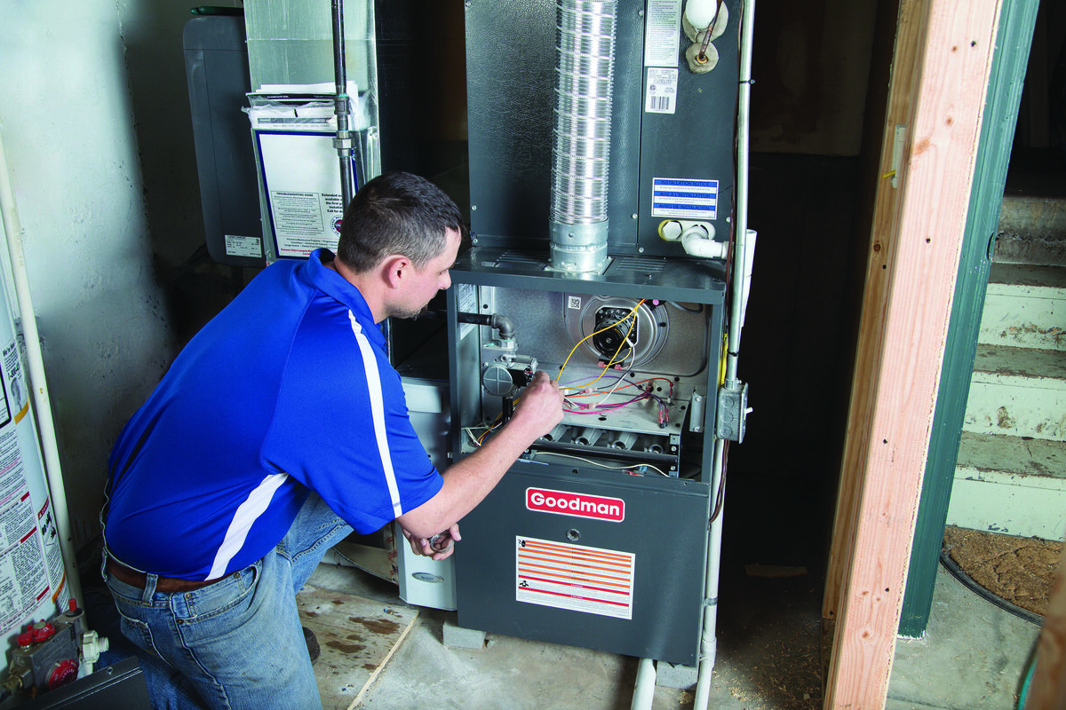 HVAC technician working on a furnace in a utility room