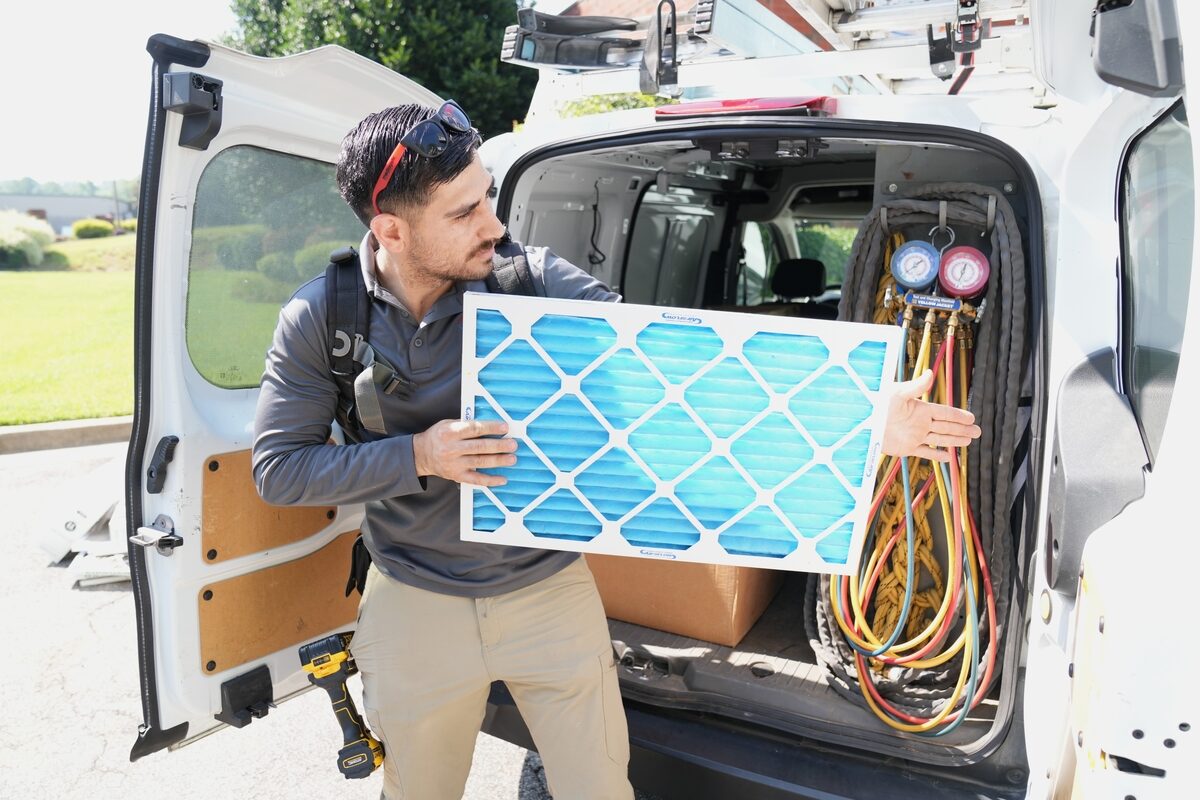 Tri-County Heating & Air technician unloading equipment from a service van