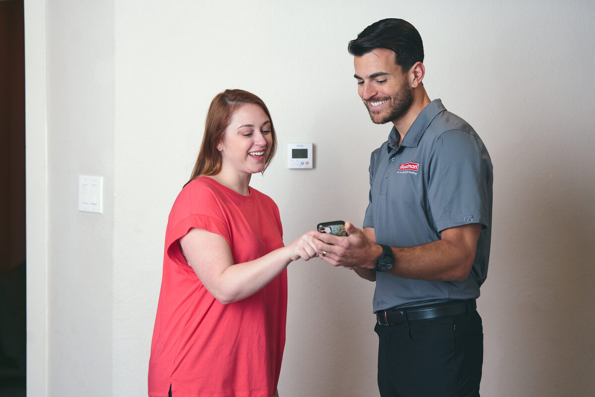 HVAC technician showing service information to a homeowner on a tablet